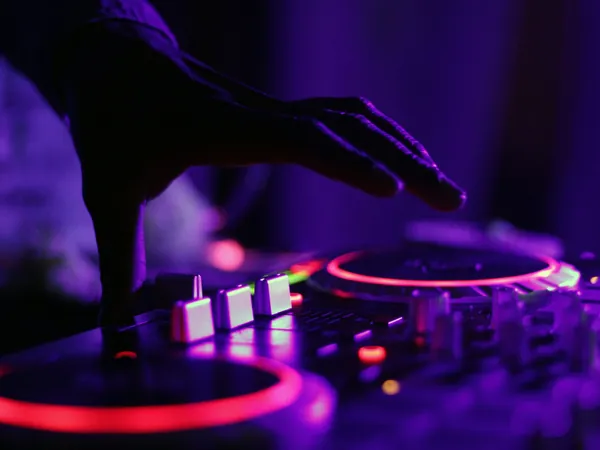 DJ mezclando en la cabina con luces moradas